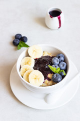 Porridge in a bowl with blueberries, banana and mint. Healthy breakfast concept