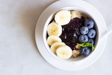 Porridge in a bowl with blueberries, banana and mint. Healthy breakfast concept