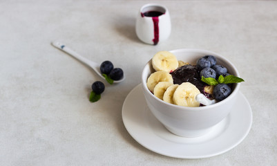 Porridge in a bowl with blueberries, banana and mint. Healthy breakfast concept