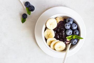 Porridge in a bowl with blueberries, banana and mint. Healthy breakfast concept
