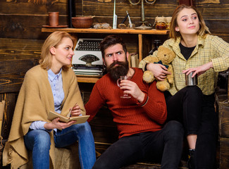 Parents spending time with their teenage daughter, upbringing concept. Bearded man sitting between his wife and daughter on wooden bench, family time. Father and girl surprised by some noise in house