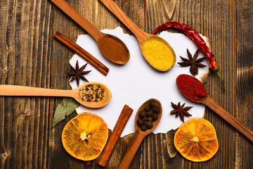 Culinary recipe concept. Piece of paper on wooden background. Cinnamon, dried orange and pepper, star anise lay around blank paper for recipe, copy space. Spices, kitchen herbs lay around white paper