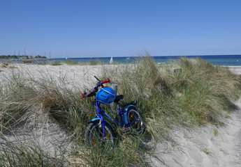 blaues Kinderfahrrad mit einem blauen Sturzhelm, unterwegs In den Dünen vor der Ostsee am...