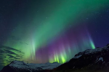 Foto auf Glas Northern lights above snowy mountains on Iceland © Franz
