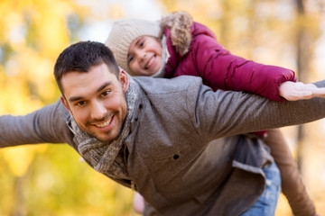 family, season and people concept - happy father and little daughter playing at autumn park