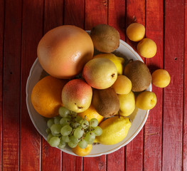 Fruit in a plate on a red wooden table.