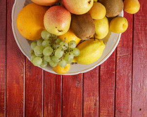 Fruit in a plate on a red wooden table.