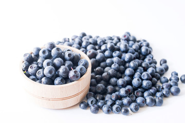 Blueberries in a wooden cup on a white background closeup, top view.