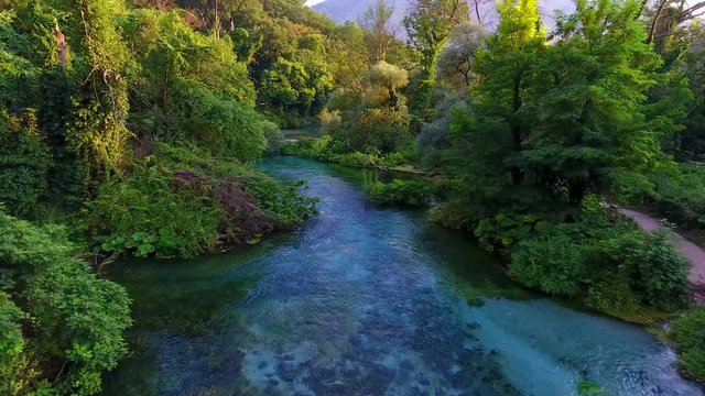Aerial. The Blue Eye (Albanian: Syri i Kalter, is a water spring near Muzine in Vlore County, southern Albania. A popular tourist attraction. Mountains and river footage.