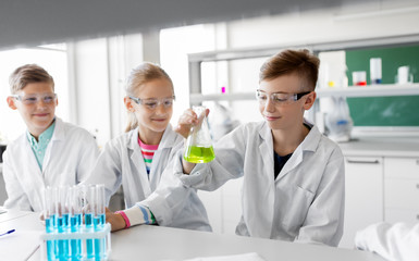education, science and children concept - kids with test tubes studying chemistry at school laboratory