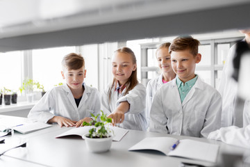 education, science and school concept - kids or students with plant at biology class