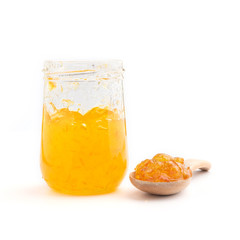 Open jar of orange jam and a spoon, isolated on white.