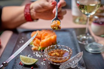 Fresh tartar with salmon, avocado, red caviar on black plate