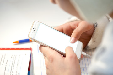 A smartphone with a white blank screen in the hands of a student, a finger points to the screen, mock-up.