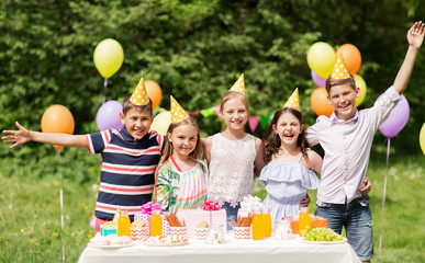 holidays, childhood and celebration concept - happy kids hugging on birthday party at summer garden