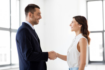 business people, partnership and cooperation concept - happy smiling businesswoman and businessman shake hands at office