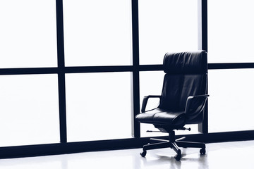 Black executive leather chair in empty office space with large window ,copy space.