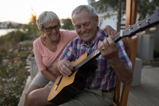 Senior couple playing guitar in the porch