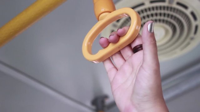 Close up of a woman hand grabbing a handle on a moving bus
