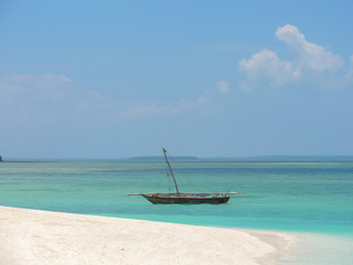 Naklejka na ściany i meble Fisherman fishing and sails on a wooden boat on clear blue water along a tropical exotic beach in Africa. Indian Ocean, Zanzibar