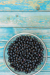 Fresh black currant on a wooden background, top view