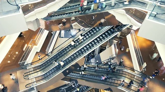 People on many fast moving Escalators In big modern shopping mall. Consumption concept. Time lapse