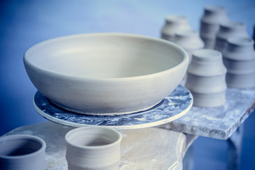 Ceramic clay products stand on the shelf close-up. Sculptor sculpts pots products from white clay. Dark. Workshop pottery. Master crock. Cultural traditions. Handmade. Craft. Twisted potter's wheel.