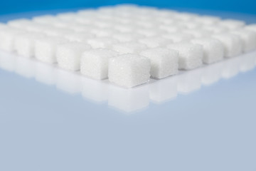 Table top shot Group of Sugar cubes vary position on light blue background