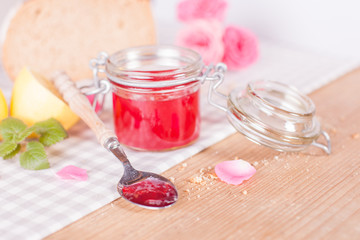 Jam jar with spoon and rose petals