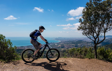 Fototapeta na wymiar Scenic view of male mountain biker on an electric bike with Barcelona City in the background