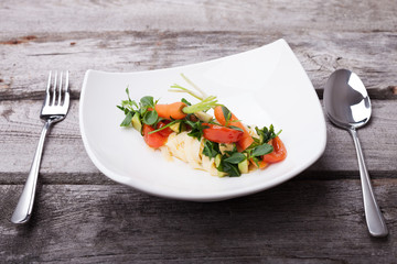 Delicious pasta dish with carrots and herbs on an old wooden table