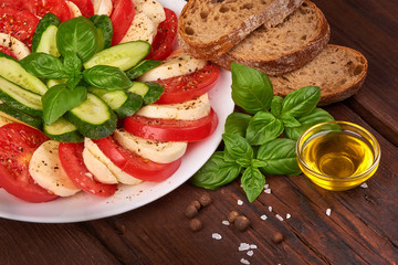 Caprese Salad. Tomato and Mozzarella slices with basil leaves with ciabatta bread on wooden background.