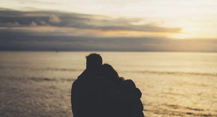 Couple hugging on beach ocean sunrise, meeting silhouette two romantic people cuddling and looking...