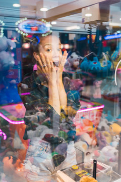 Shocked woman looking at toys in claw machine