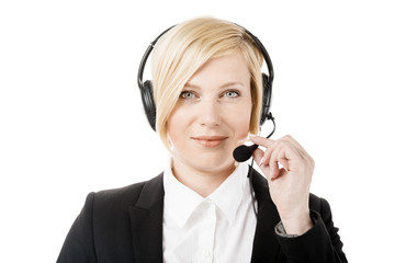 Concentrated call center operator, blonde woman dressed in black jacket and white shirt working on laptop via headset in white office