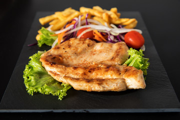 Juicy grilled chicken breast steak with fresh vegetables and french fries