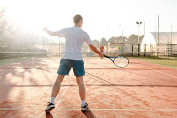  Man playing tennis in the morning in sunlight