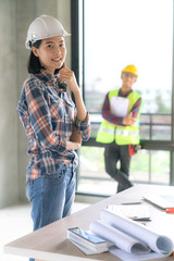 Portrait of asian architect woman with casual costume on construction officer working with drawing in background on home renovation site