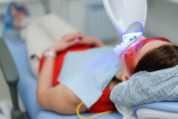 the patient undergoes a procedure for teeth whitening with an ultraviolet lamp