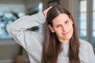 Young beautiful woman at home confuse and wonder about question. Uncertain with doubt, thinking with hand on head. Pensive concept.