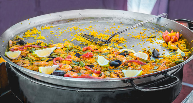 Traditional spanish seafood paella in large pot at a street food market.