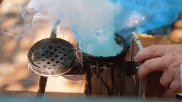 bee-maker of a smoke pipe beeper smoker device for repelling evil bees. slow motion video apiary. beekeeping concept lifestyle bee agriculture