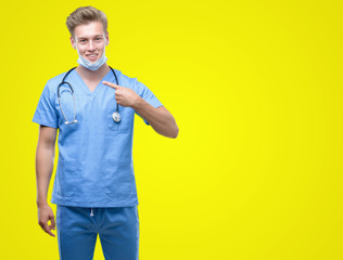 Young handsome blond doctor with surprise face pointing finger to himself