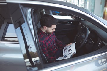 Salesman reading brochure inside the car