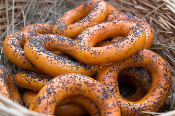 Dryers, bagels, golden baked and sweet round buns with poppies in the form of rings in wicker baskets made from a vine. Appetizing traditional flour products, dessert and snack for tea and drinks