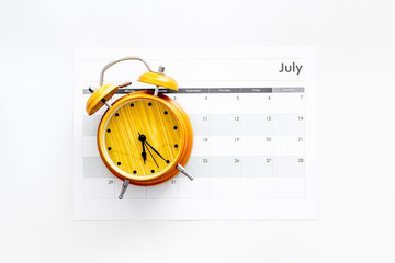 Deadline concept. Alarm clock on calendar on white background top view copy space