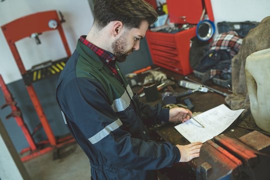 Mechanic reading instruction manual in garage