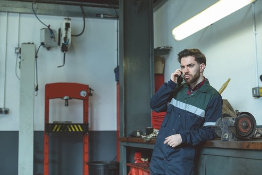 Mechanic talking on cell phone while standing in garage