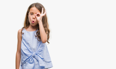 Brunette hispanic girl doing ok gesture shocked with surprised face, eye looking through fingers. Unbelieving expression.