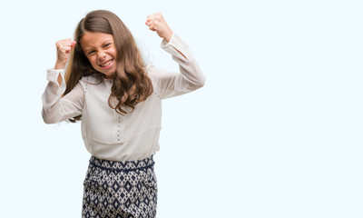 Brunette hispanic girl very happy and excited doing winner gesture with arms raised, smiling and screaming for success. Celebration concept.